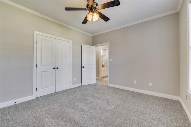 unfurnished bedroom with a closet, baseboards, ornamental molding, a ceiling fan, and carpet