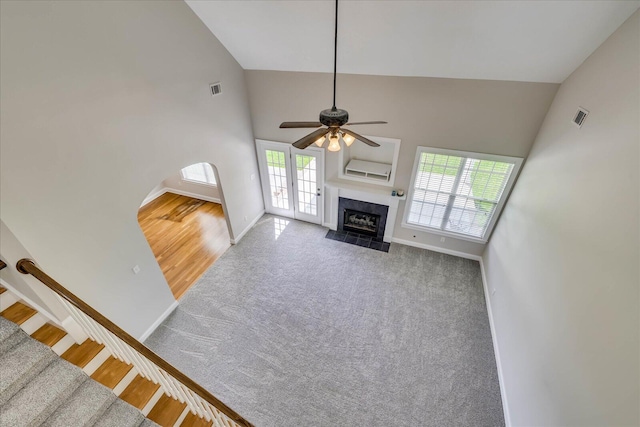 unfurnished living room featuring carpet flooring, visible vents, ceiling fan, high vaulted ceiling, and a high end fireplace