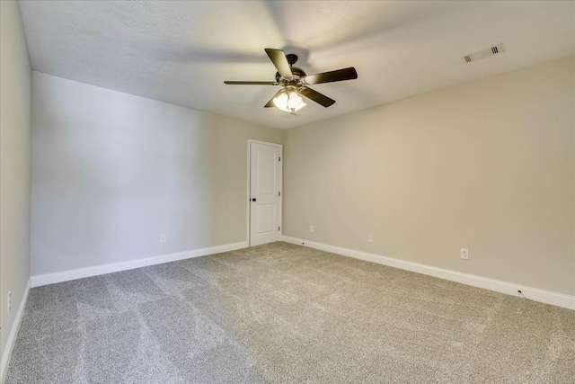 carpeted spare room featuring visible vents, baseboards, and a ceiling fan
