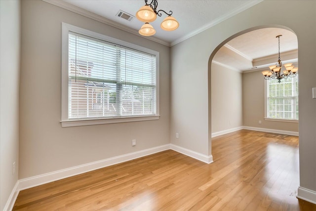 spare room with baseboards, an inviting chandelier, ornamental molding, light wood-style flooring, and arched walkways