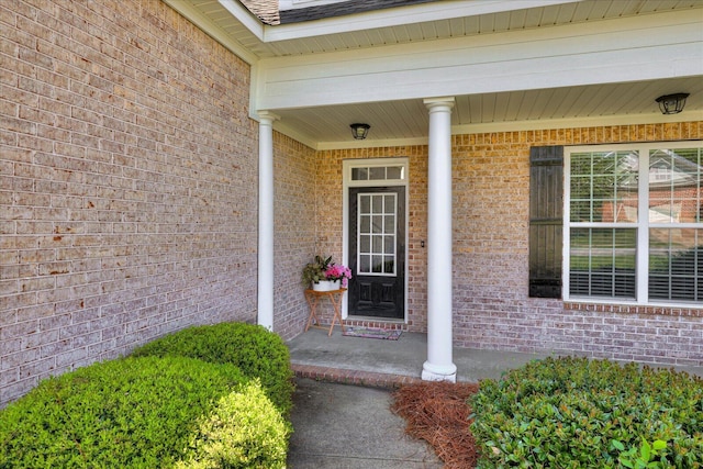view of exterior entry with covered porch and brick siding