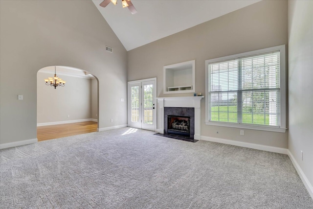 unfurnished living room with a fireplace, visible vents, high vaulted ceiling, arched walkways, and ceiling fan with notable chandelier