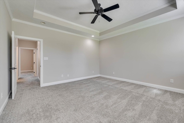carpeted empty room featuring baseboards, a ceiling fan, crown molding, and a raised ceiling