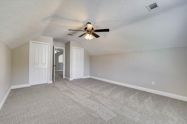 additional living space featuring a ceiling fan, a textured ceiling, carpet, and visible vents
