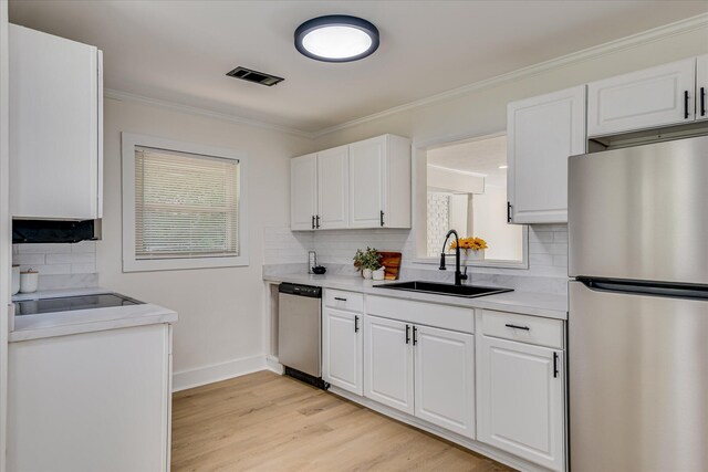 2281 Raleigh Dr, Augusta, GA 30904 - kitchen featuring appliances with stainless steel finishes, a sink, white cabinets, crown molding, and backsplash