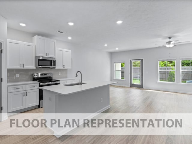 1307 Newbern Dr, Grovetown, GA 30813 - kitchen with stainless steel appliances, light wood-style floors, a center island with sink, tasteful backsplash, and light countertops