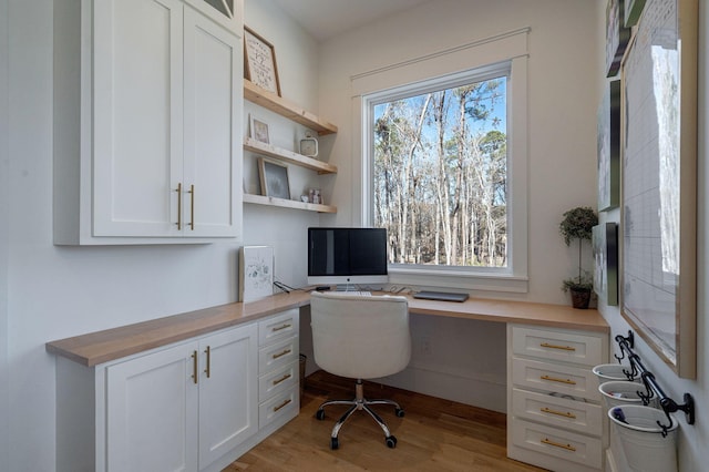 office featuring built in desk and light hardwood / wood-style floors