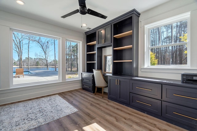 unfurnished office with a wealth of natural light, dark wood-type flooring, and built in desk