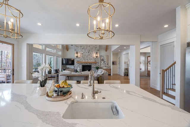 kitchen featuring light stone counters, sink, decorative light fixtures, and a chandelier