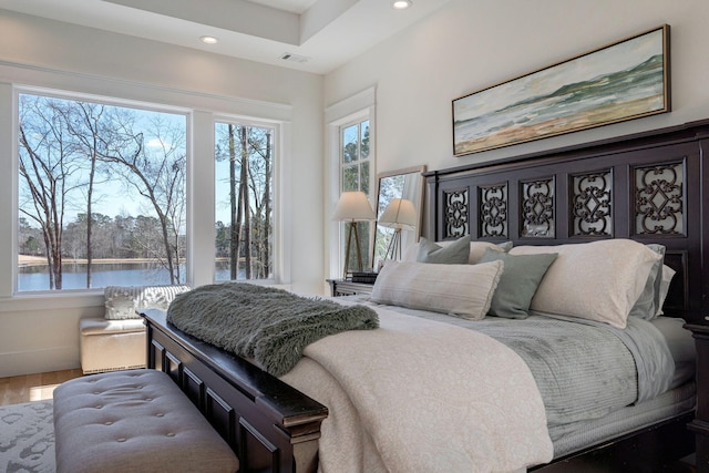 bedroom featuring a water view and hardwood / wood-style floors