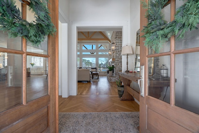 hall with parquet flooring, a high ceiling, and plenty of natural light