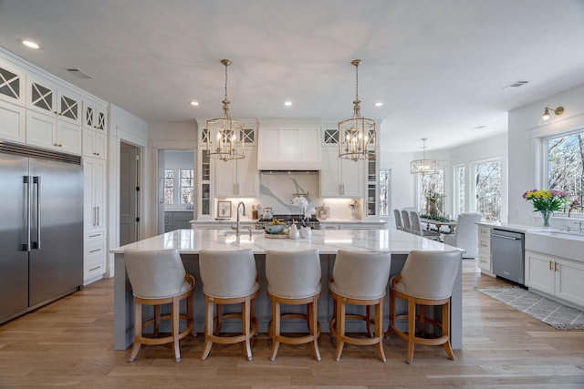 kitchen with a kitchen island with sink, decorative light fixtures, stainless steel appliances, and a kitchen bar