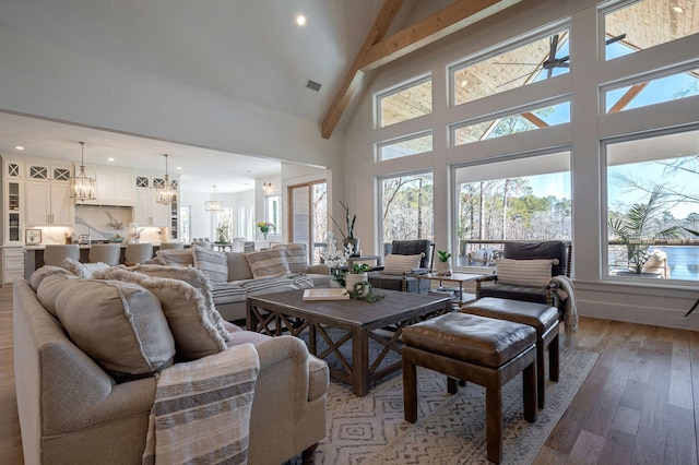 living room with an inviting chandelier, wood-type flooring, and high vaulted ceiling