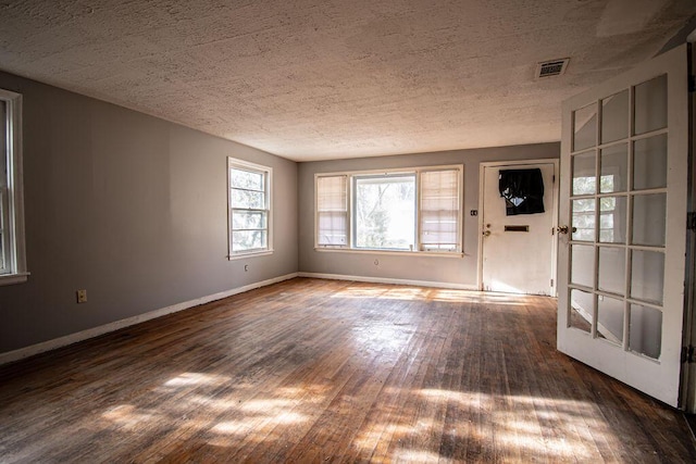 spare room with visible vents, a textured ceiling, baseboards, and wood finished floors
