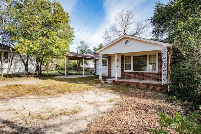 view of front facade with a carport, covered porch, brick siding, and driveway