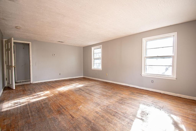 spare room featuring baseboards, a textured ceiling, and hardwood / wood-style floors