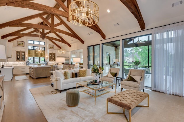 living area featuring high vaulted ceiling, light wood-style flooring, visible vents, and an inviting chandelier