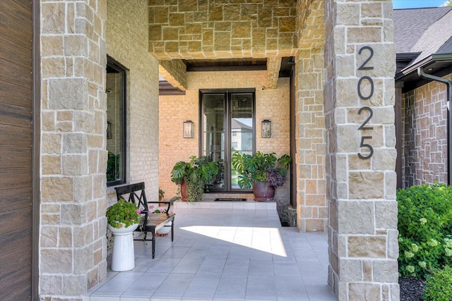 doorway to property featuring stone siding, brick siding, and french doors