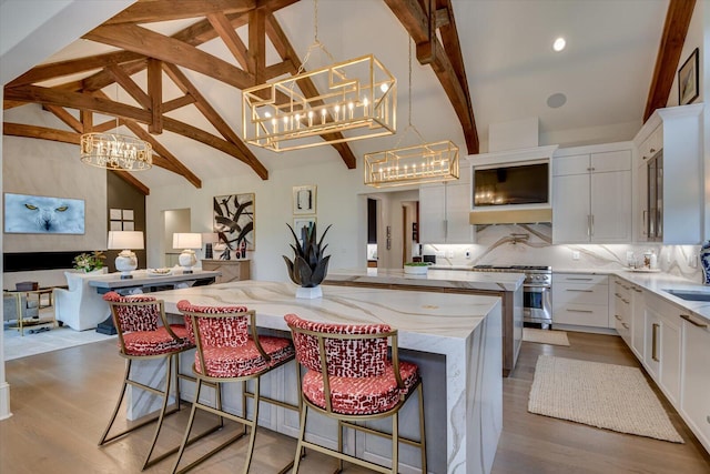 kitchen featuring light stone counters, a spacious island, high end stainless steel range, tasteful backsplash, and an inviting chandelier