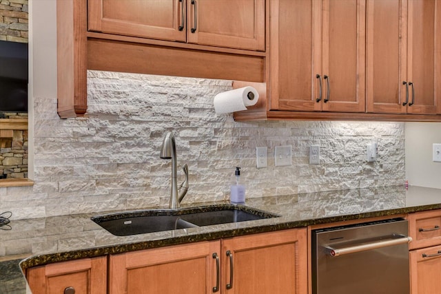 kitchen featuring backsplash, stainless steel dishwasher, dark stone counters, and a sink