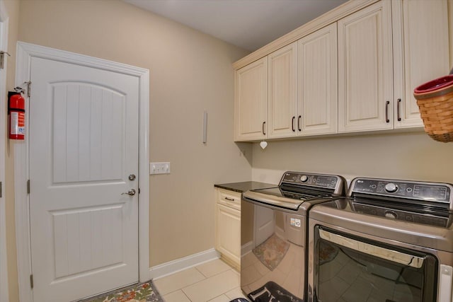 clothes washing area featuring light tile patterned flooring, cabinet space, independent washer and dryer, and baseboards