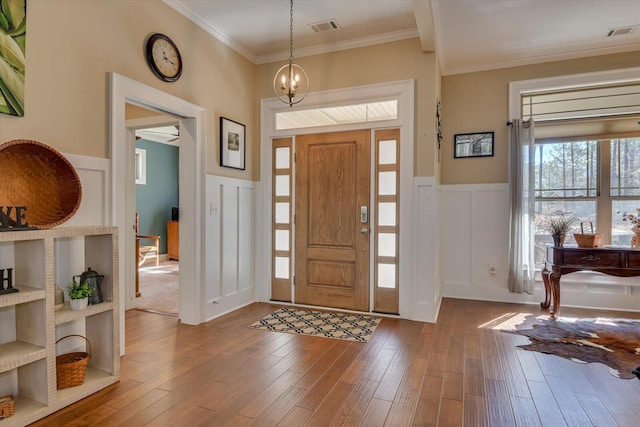 foyer featuring visible vents, crown molding, and wood finished floors