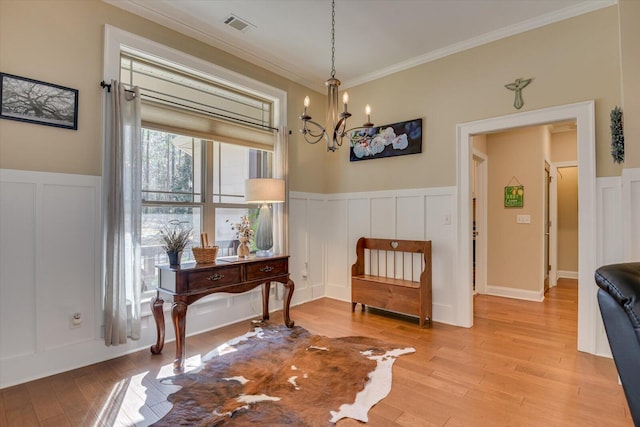 living area with a notable chandelier, light wood-style flooring, crown molding, and visible vents