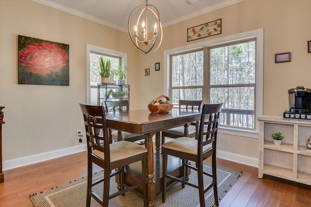 dining area with a wealth of natural light, dark wood-type flooring, a chandelier, and crown molding