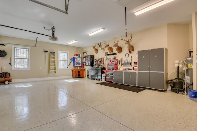 garage featuring a workshop area, electric water heater, a garage door opener, and baseboards