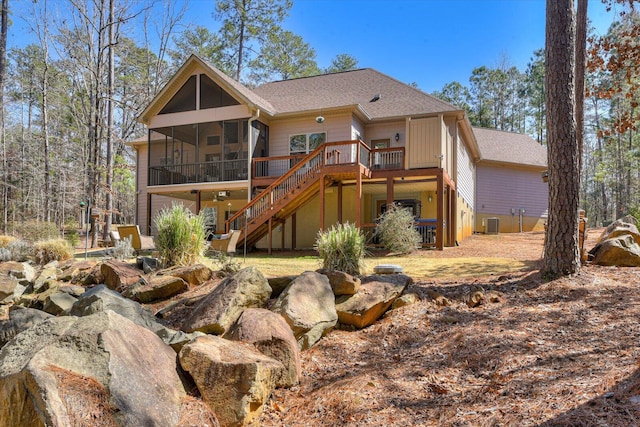 rear view of house with cooling unit, roof with shingles, a sunroom, a wooden deck, and stairs