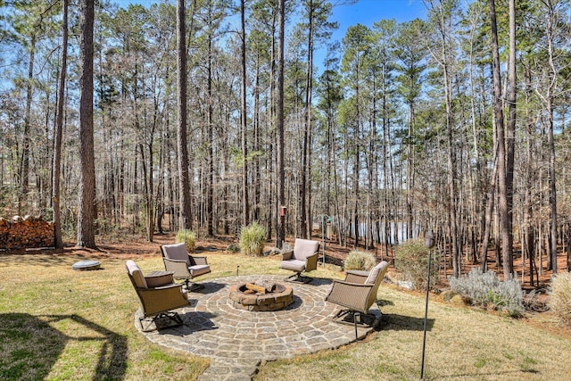 view of yard featuring a patio, a fire pit, and a view of trees