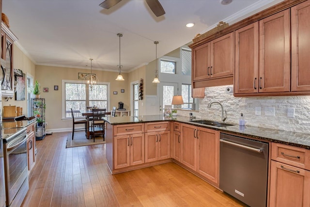 kitchen with a sink, dark stone counters, appliances with stainless steel finishes, light wood finished floors, and decorative backsplash