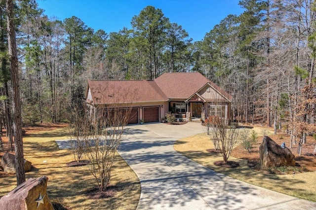 view of front of home with a forest view, a garage, and driveway