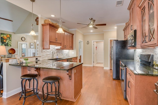 kitchen featuring visible vents, a peninsula, ceiling fan, appliances with stainless steel finishes, and brown cabinets