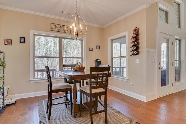 dining area with visible vents, wood-type flooring, a notable chandelier, and crown molding