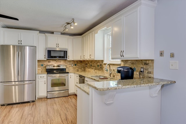 307 Candlewood Dr, Martinez, GA 30907 - kitchen featuring appliances with stainless steel finishes, a sink, a peninsula, white cabinetry, and light stone countertops