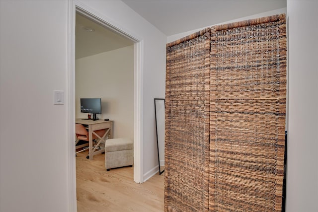 hallway with light wood finished floors and an office area