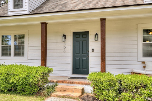entrance to property with roof with shingles and covered porch