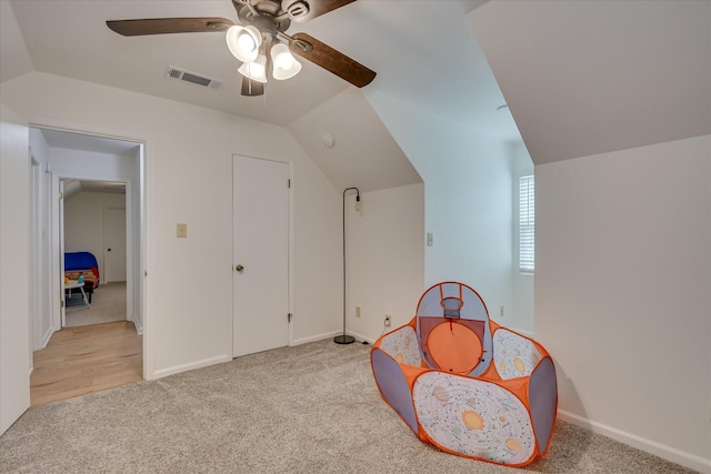recreation room featuring light carpet, ceiling fan, vaulted ceiling, and baseboards
