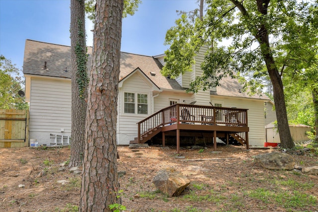 back of property featuring stairs, a deck, and a shingled roof