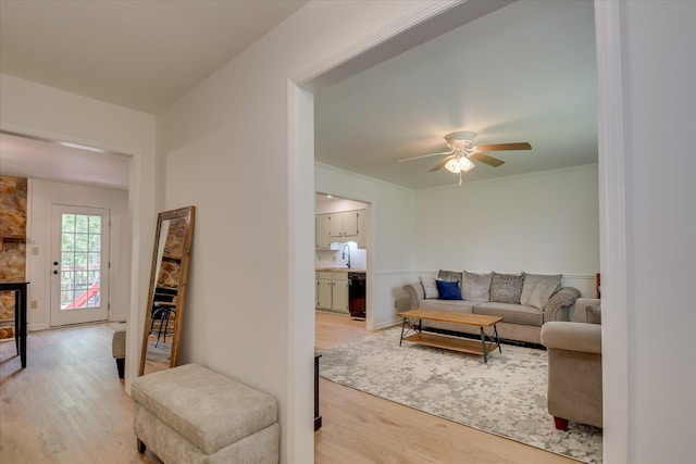 living room with light wood-style floors, ceiling fan, and baseboards