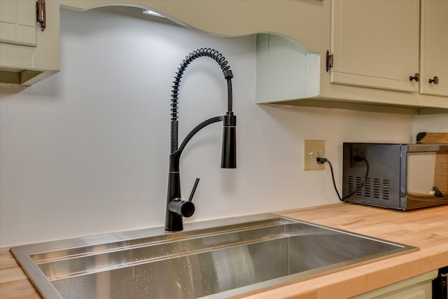 kitchen view of black microwave, wooden counters, and a sink