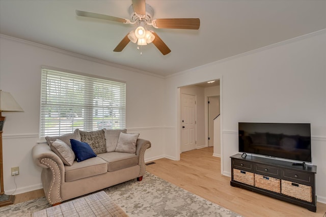 living area featuring wood finished floors, ornamental molding, a ceiling fan, and baseboards