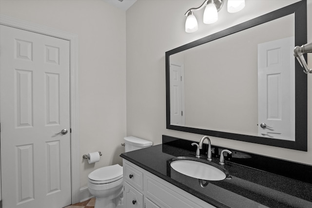 bathroom with toilet, vanity, and tile patterned floors