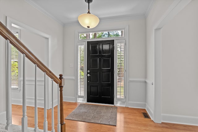 foyer entrance featuring light wood finished floors, stairway, healthy amount of natural light, crown molding, and baseboards