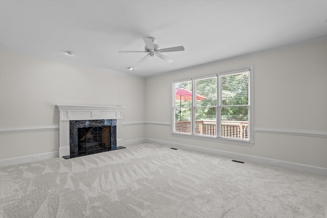 unfurnished living room with ceiling fan, ornamental molding, a premium fireplace, carpet flooring, and baseboards