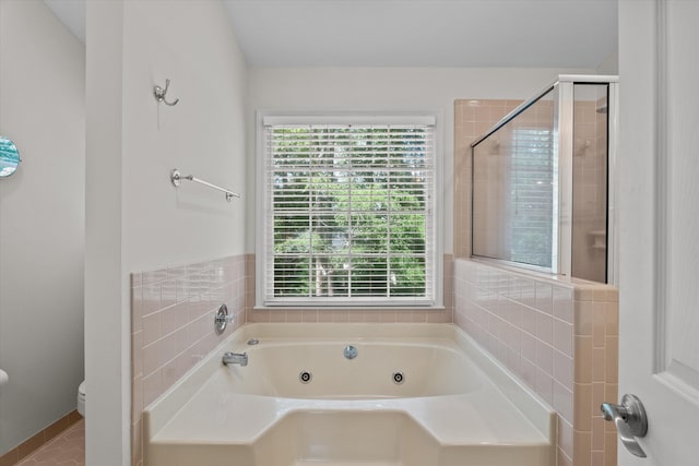 bathroom featuring healthy amount of natural light, a tub with jets, toilet, and a stall shower