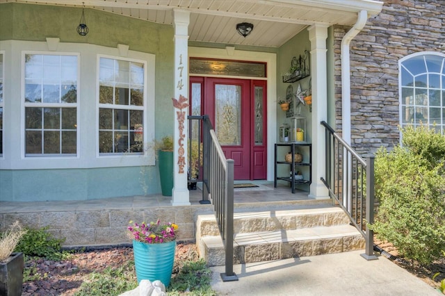 view of exterior entry featuring stone siding and stucco siding