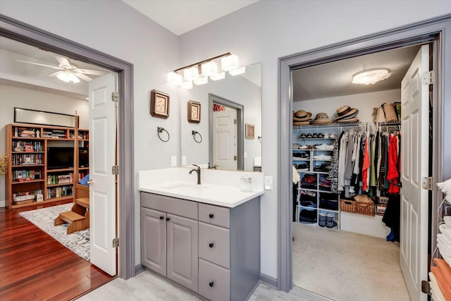 bathroom featuring vanity, a walk in closet, ceiling fan, and wood finished floors