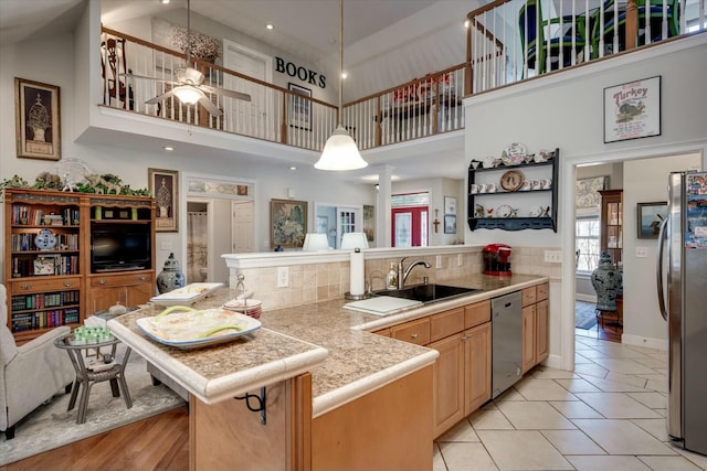 kitchen featuring ceiling fan, decorative light fixtures, a peninsula, stainless steel appliances, and a sink